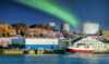 Industriområde i Nord-Norge med skip ved kai og store lagringstanker i bakgrunnen, opplyst av nordl